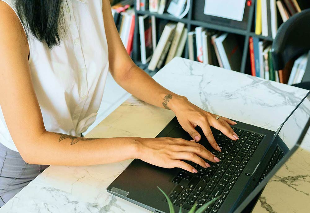 Mujer especializada en traducción jurada oficial tecleando en un portátil.